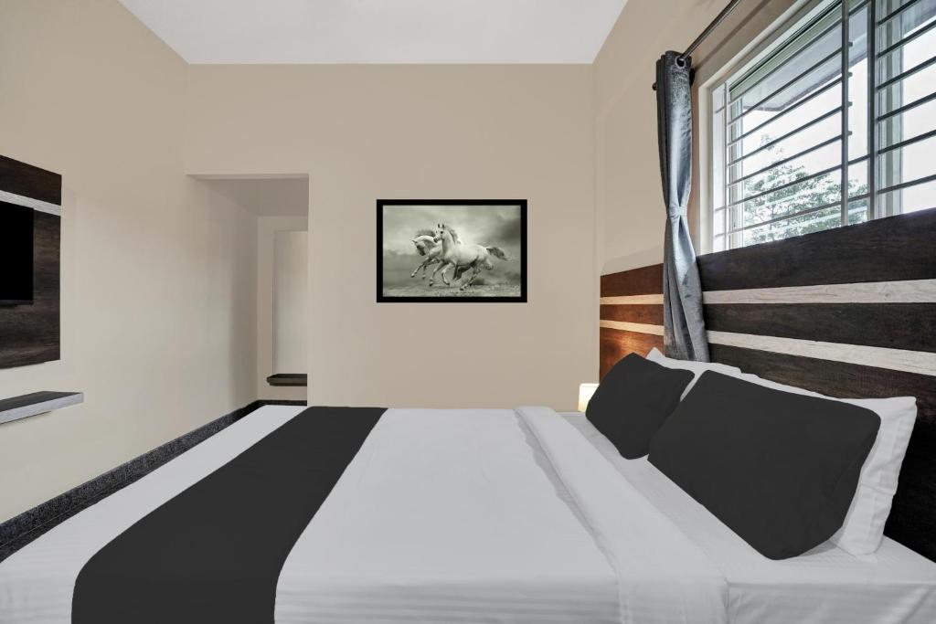 a bedroom with a black and white bed and a window at Super Collection O Peenya 2nd stage Formerly the JK Grand in Bengaluru