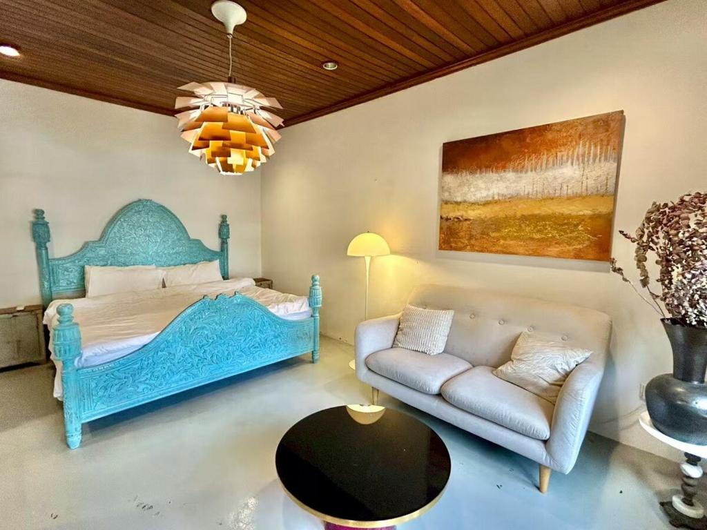 a bedroom with a blue bed and a couch at Chic Designer Master Bedroom in Shared Bungalow near LRT SS1 PJ in Petaling Jaya