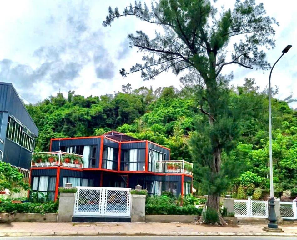 a red building with a tree in front of it at Sea la vie - Do Son Beach Homestay in Ðố Sơn