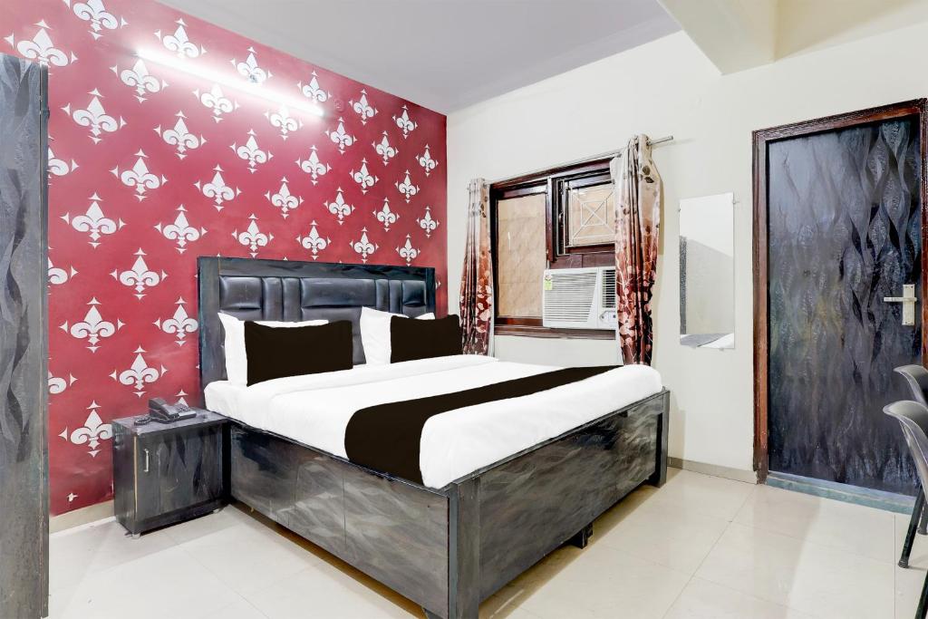 a bedroom with a bed and a red wall at Super Hotel O Nehru Nagar Near Yashodha Hospital in Ghaziabad