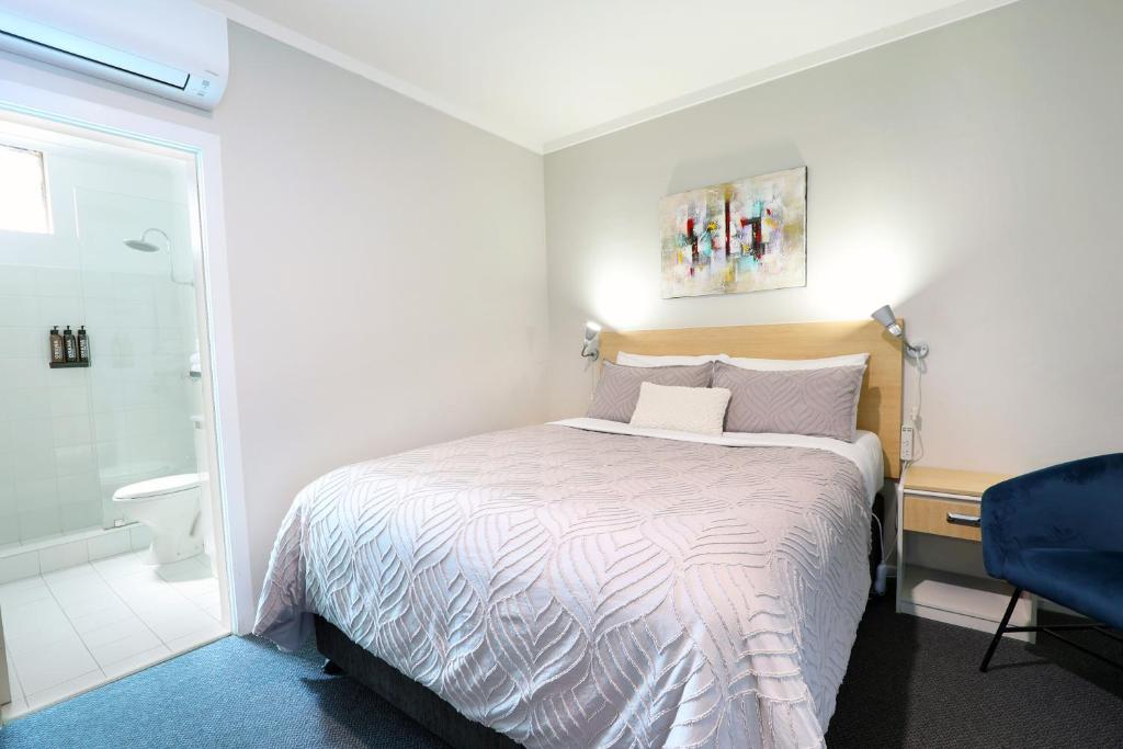 a bedroom with a bed and a bathroom with a shower at Nebula Motel in Cooma