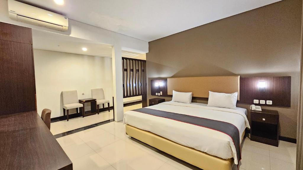 a hotel room with a large bed and a desk at Grage Hotel Malang by TOS in Malang