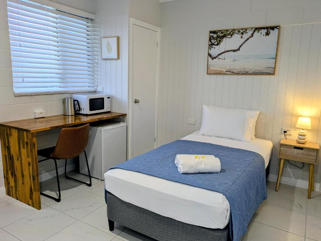 a bedroom with a bed and a desk with a microwave at Central Private Bedroom & Ensuite - City & Strand Beach Location in Townsville