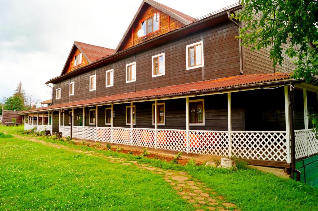 una gran casa de madera con un césped verde delante de ella en Eco Farm Usadba Kuznetsovo en Kuznetsovo