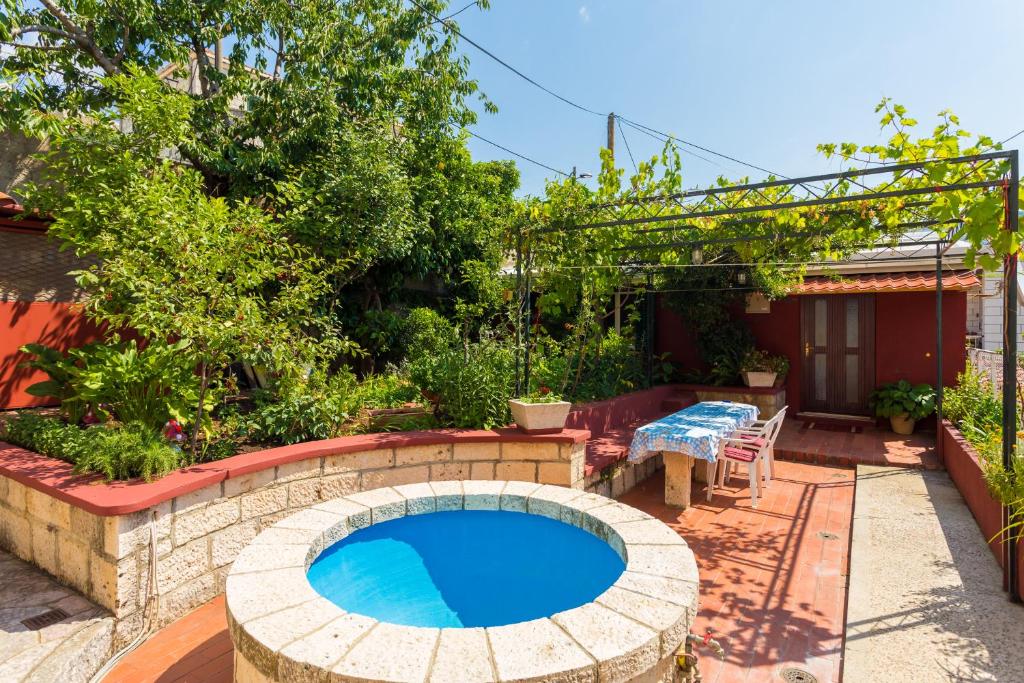 a swimming pool in a garden with a table and a patio at Apartments Afrodita in Dubrovnik