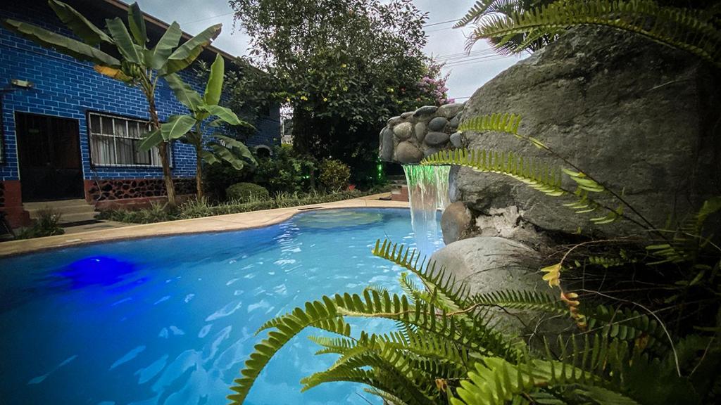 a swimming pool with a waterfall next to a house at Hostal el Bosque de Mindo in Mindo