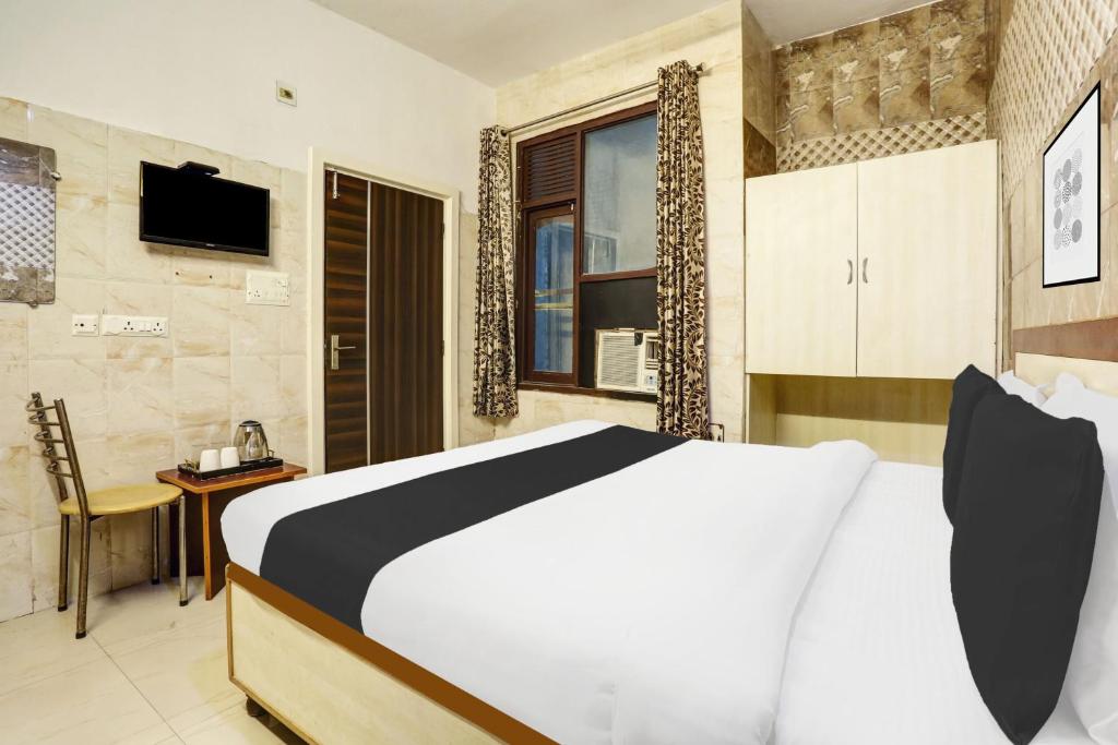 Un dormitorio con una cama grande y un televisor. en Hotel O Jammu Near Ragunath Bazaar Formerly GoodWill, en Jammu