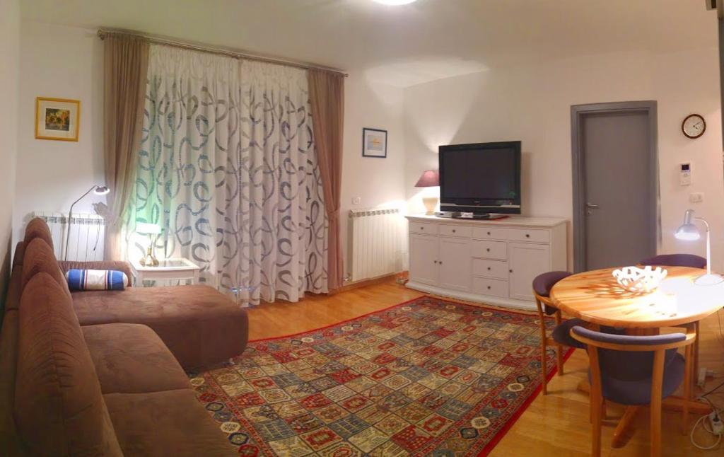 een woonkamer met een bank, een tv en een tafel bij Brand New Place in Rovinj