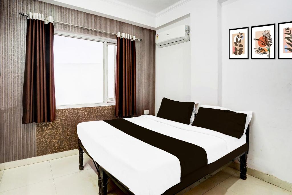 a bedroom with a large white bed with a window at Super Hotel O Jagatpura Near JTM Mall Formerly Royan Inn in Jaipur