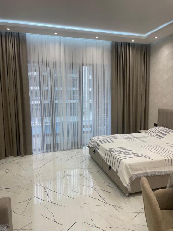 a bedroom with a king sized bed and large windows at Sea breeze, studio apartment in Nardaran