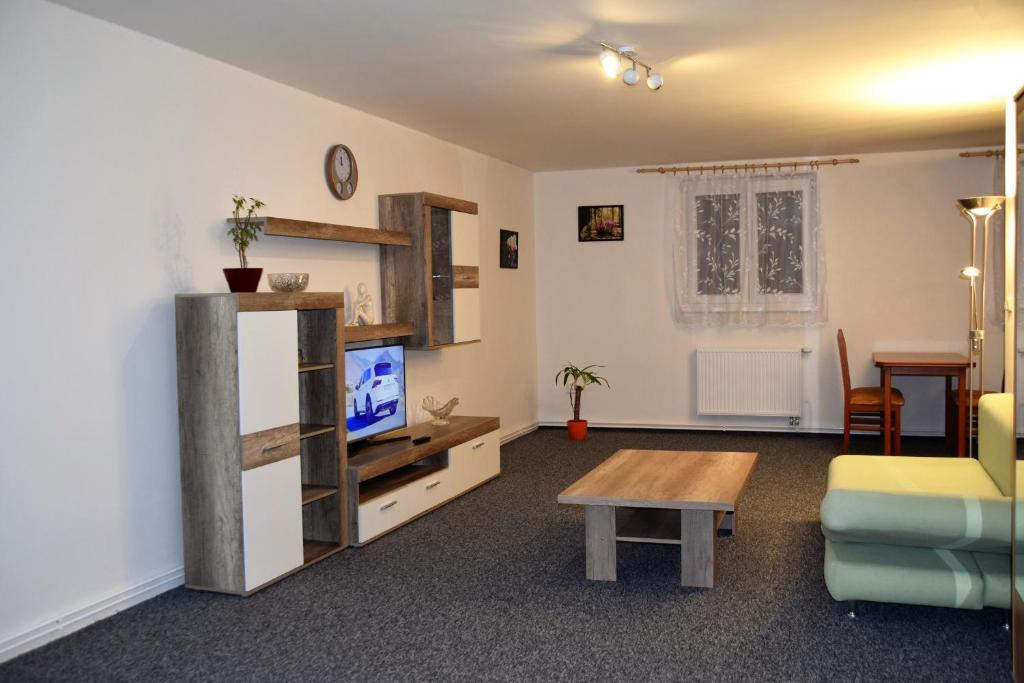 sala de estar con sofá, TV y mesa en Apartmán Černá v Pošumaví, en Černá v Pošumaví