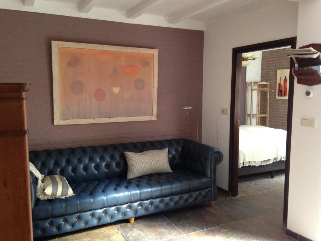 a black leather couch in a room with a bedroom at Hofje7 in Groesbeek