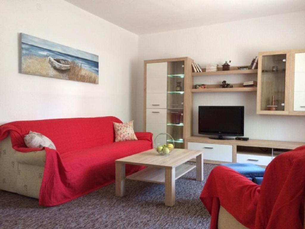 salon z czerwoną kanapą i telewizorem w obiekcie House For Holidays Kozul w Ražancu