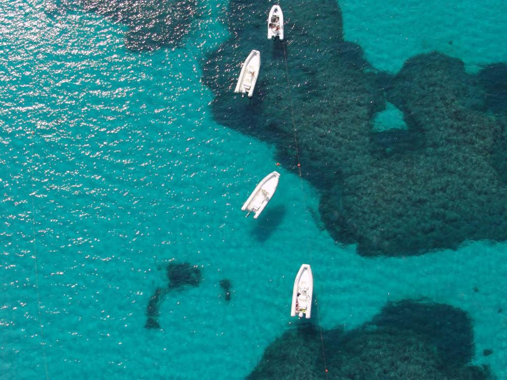 three boats in the water next to a island at Sa Tirìa in Chia