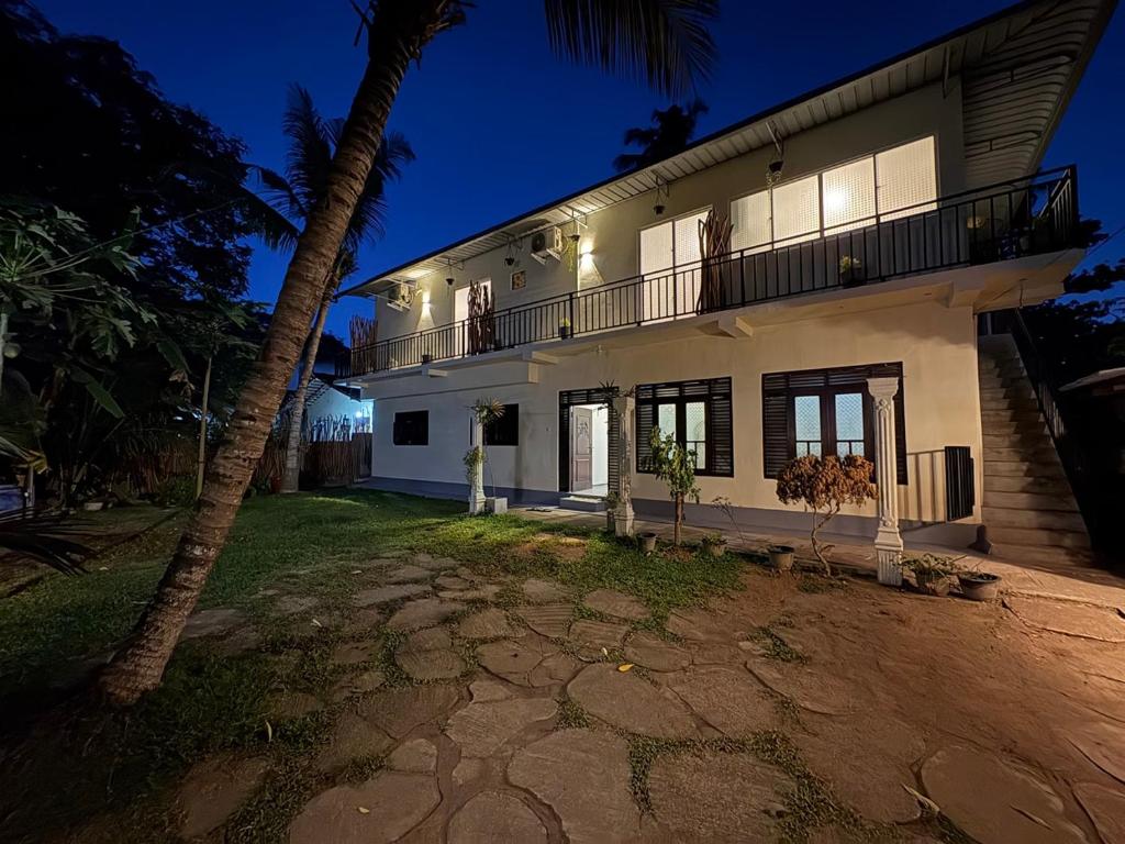a white house with a balcony and a palm tree at Wake N Flow, Ahangama - Kabalana Beach in Ahangama