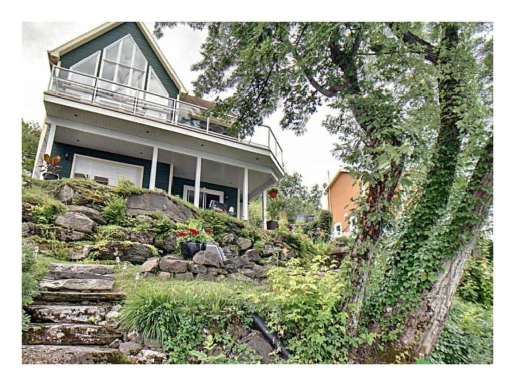 a house sitting on top of a hill with stairs at Lakefront Spa - Chez Bernard L'Hermite in St-Ferdinand