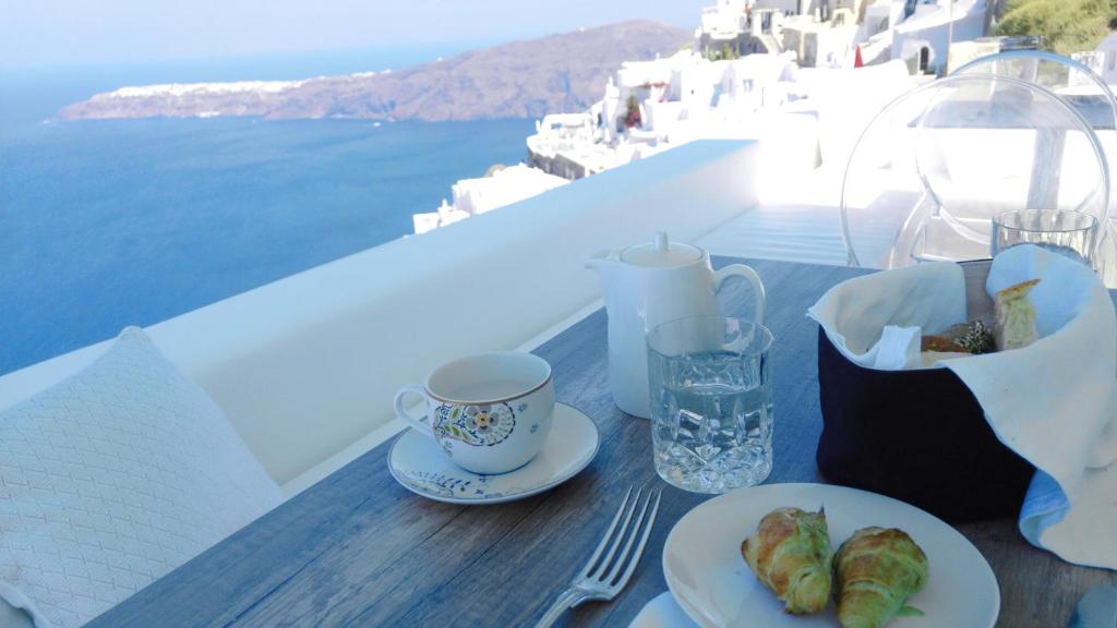 un tavolo con piatti e una tazza di caffè di Andronikos Santorini a Imerovigli