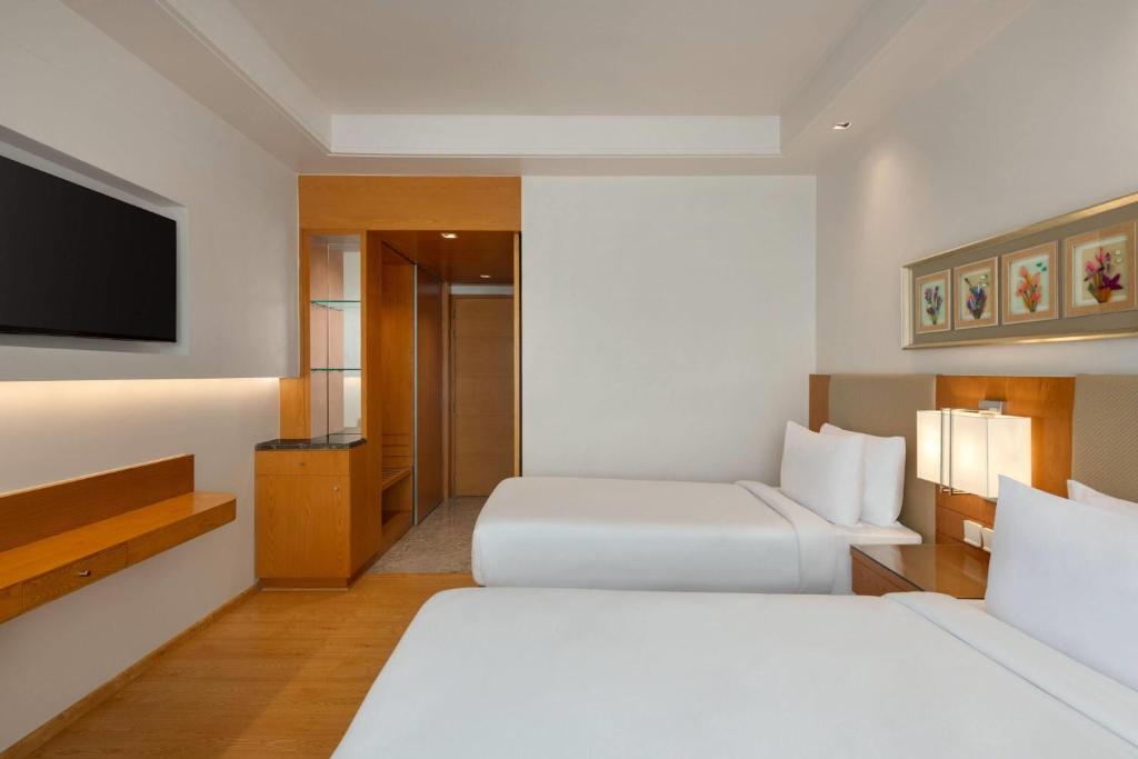 una camera d'albergo con due letti e una TV a schermo piatto di Ramada by Wyndham Ghaziabad Vasundhara a Ghaziabad