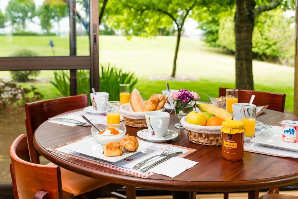 Brit Hotel Rennes Cesson في سيسو سُفْيينْ: طاولة خشبية عليها طعام الإفطار