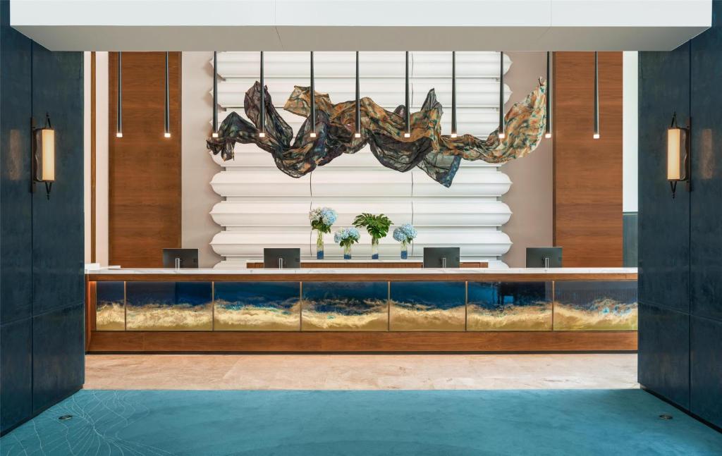 A polished reception desk framed by dark walls and a sculptural fish installation.