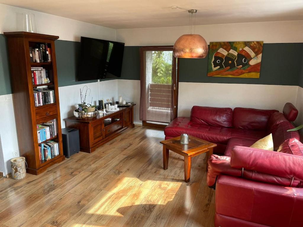 ブラウボイレンにある3 Zimmer Ferienwohnung Blaubeurenの赤いソファとテレビのあるリビングルーム