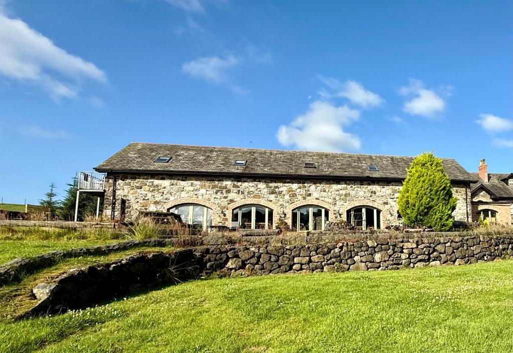 ein Steinhaus mit einer Steinmauer auf einem Feld in der Unterkunft Upper Barn at the Flax Mill in Coleraine