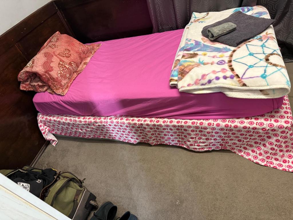 a bed with pink sheets and pillows on it at 4 bedroom English cottage with open fire place in Kalgoorlie