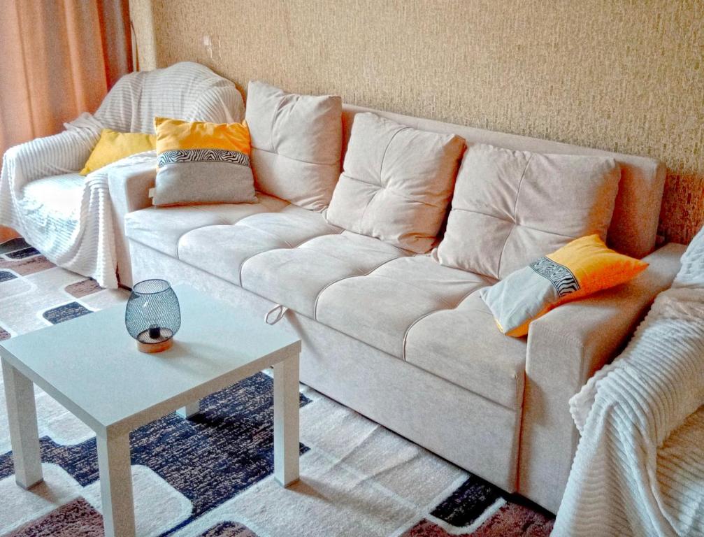 a living room with a white couch and a table at 2х комнатная квартира в центре in Ustʼ-Kamenogorsk