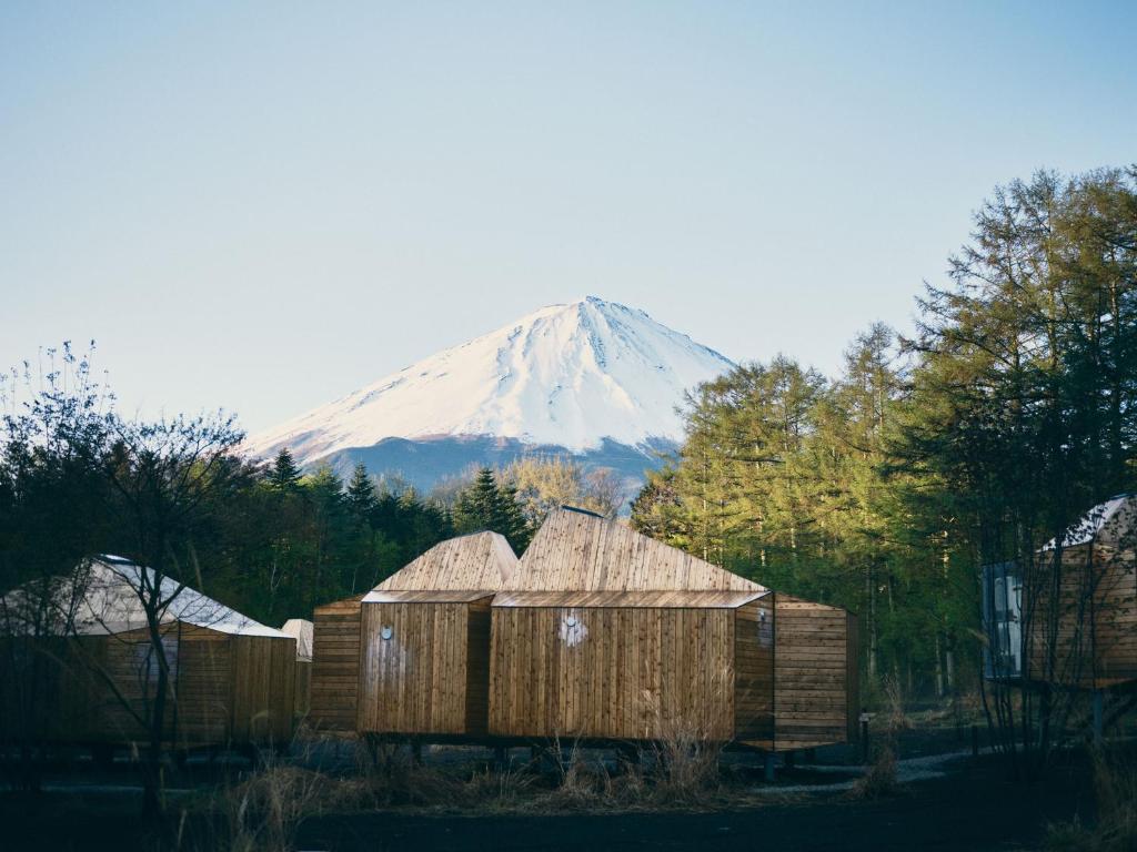 a snow covered mountain in the distance with wooden huts at SANU 2nd Home 河口湖2nd in Fujikawaguchiko