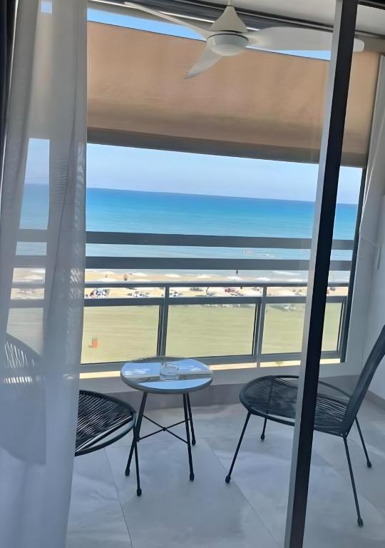 einen Balkon mit Stühlen, einem Tisch und Meerblick in der Unterkunft Lazuli Beachfront Sea View Ap 34 in Larnaka