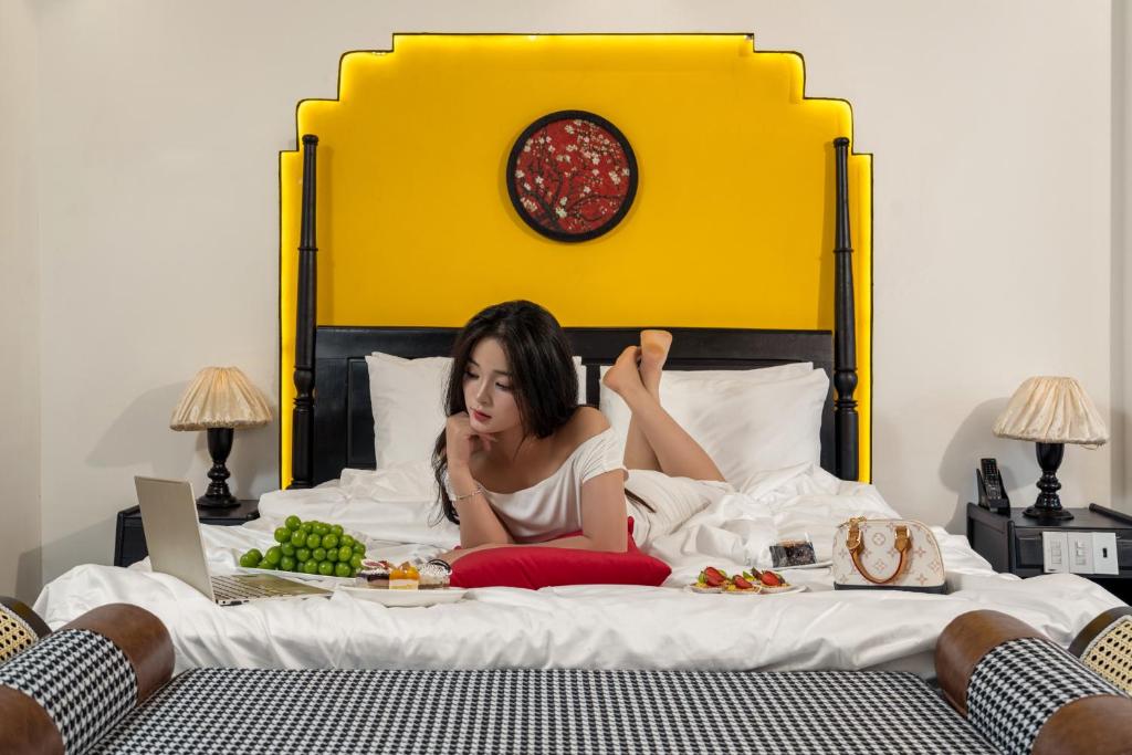 una mujer acostada en una cama con un plato de comida en Grand Fusion Point Hotel, en Hue