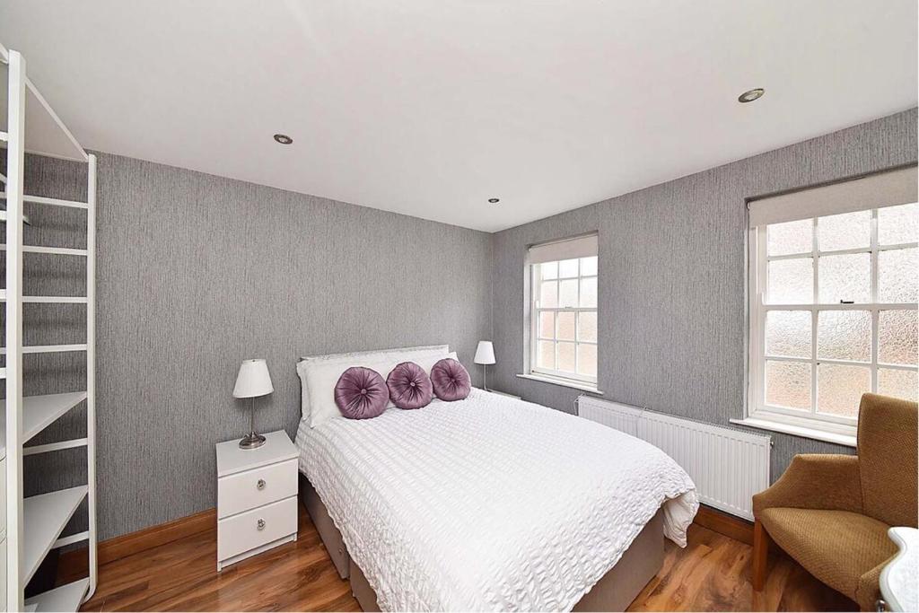 a bedroom with a bed with purple pillows on it at First Floor Central Knutsford Apartment in Knutsford