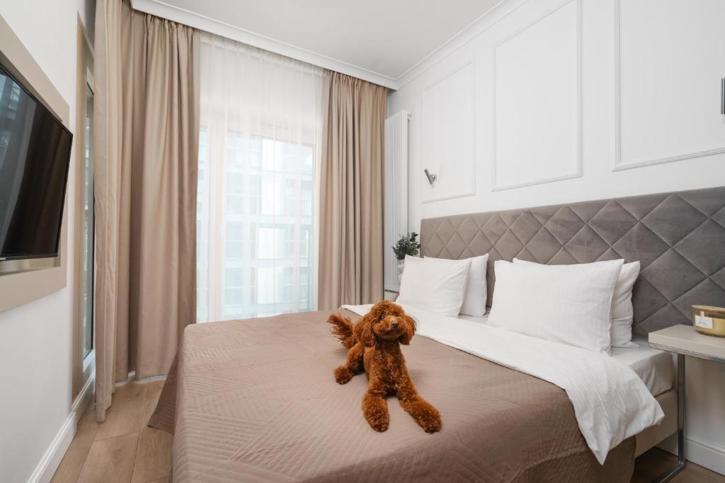 a teddy bear sitting on a bed in a bedroom at Golden Apartments - Mennica Residence Luxury Stay in Warsaw