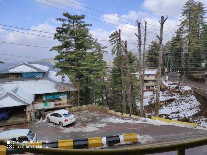 a white car parked in a parking lot with snow at Jamal Lodge & Family Flats in Dargai