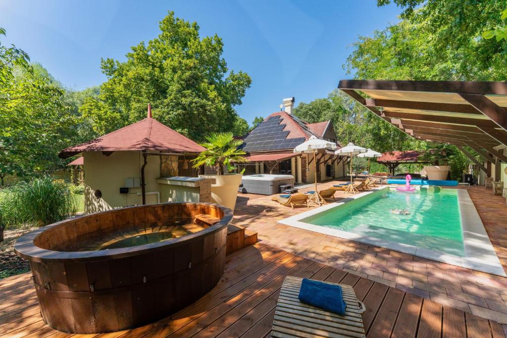 an outdoor swimming pool with a large wooden tub next to a house at Ikon Vendégház in Békéscsaba