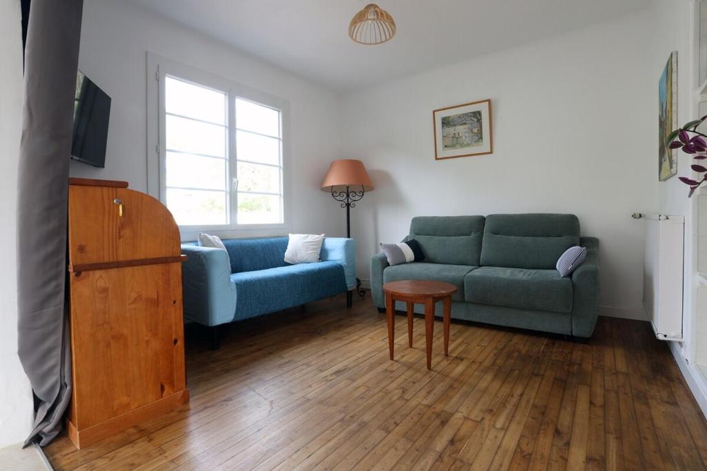 a living room with two blue couches and a tv at Maison cosy avec jardin proche plage et forêt in Grand-Village-Plage
