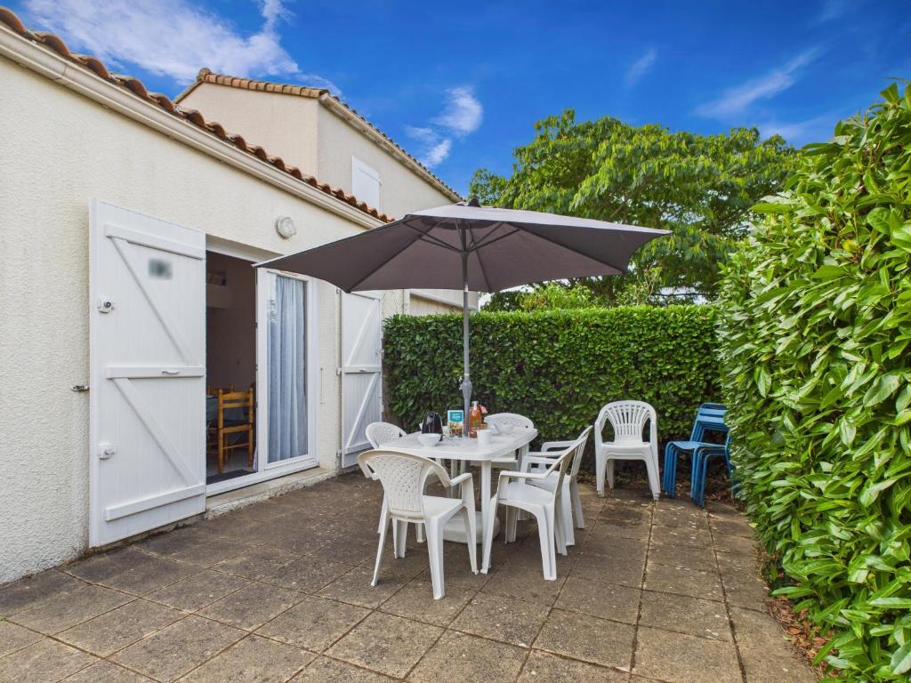 a patio with a table and chairs and an umbrella at Piscine commune, terrasse, maison pour 5 in Saint-Vincent-sur-Jard