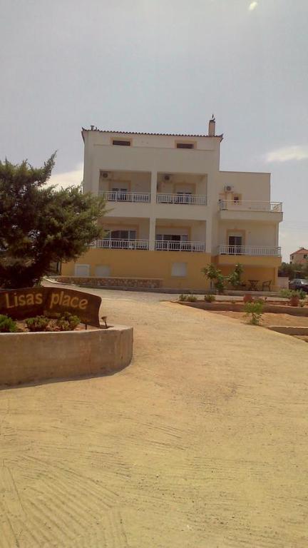 - un grand bâtiment blanc avec un panneau devant dans l'établissement Lisa's Place, à Elafonisos