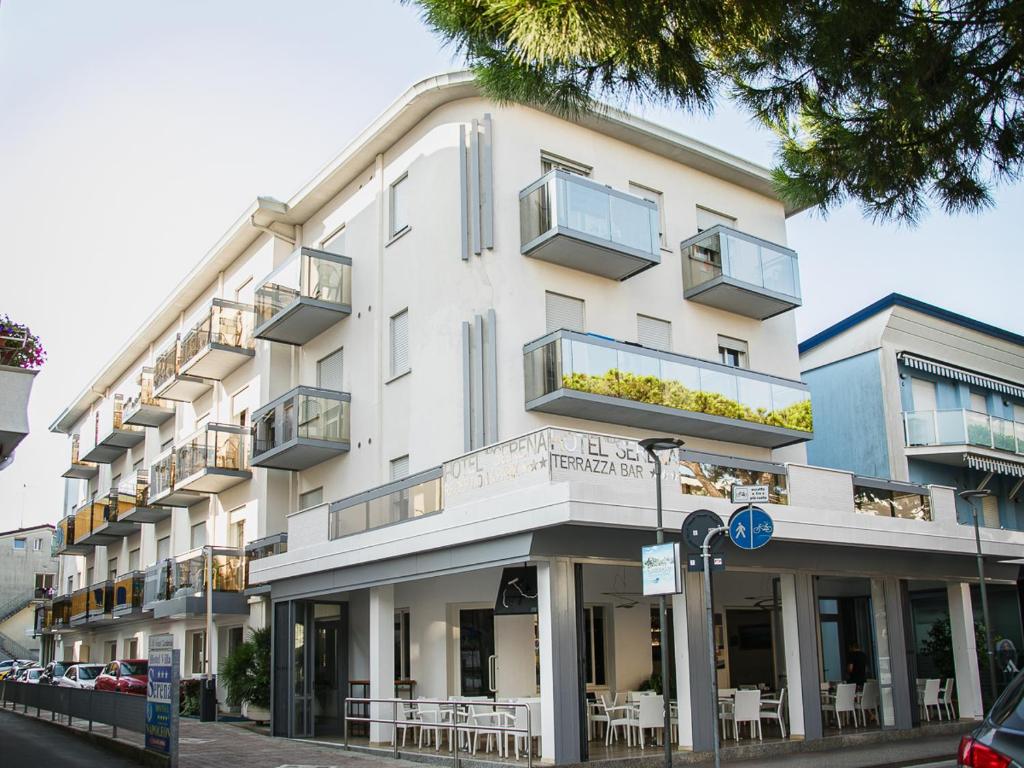 a white building with tables and chairs on a street at Villa Serena in Lido di Jesolo