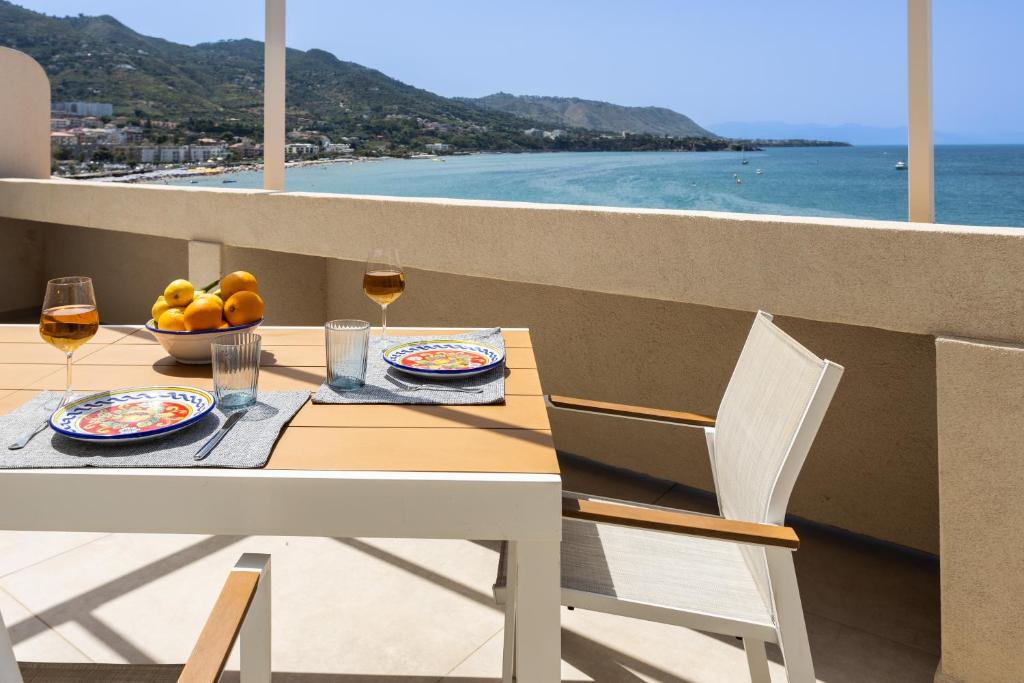 a table with a glass of wine and a bowl of fruit at AUREA collection SEA VIEW in Cefalù