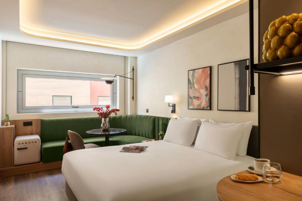 a hotel room with a large bed and a table at Serenay Málaga Hotel in Málaga
