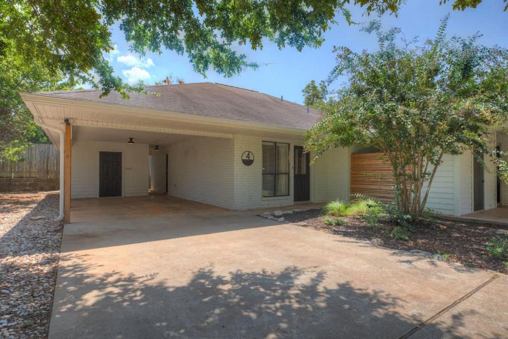 a white house with a garage and a driveway at Wanderlust #4 | Hot Tub | Shared Outdoor Space in Fredericksburg