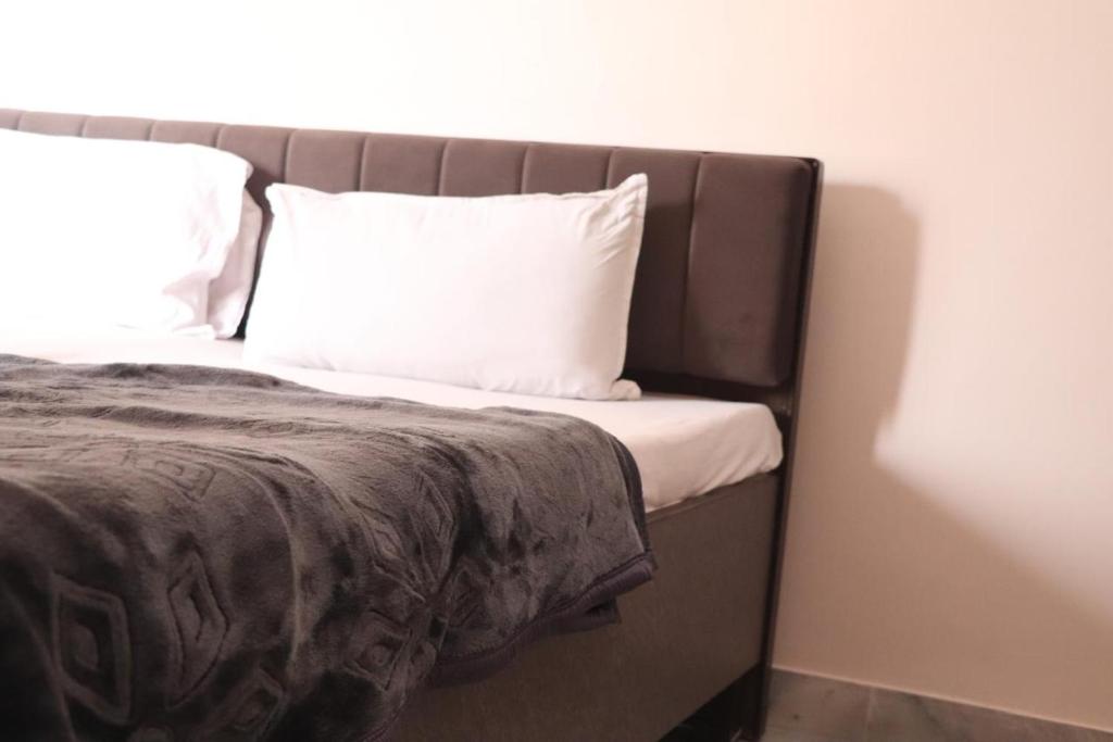 a bed with white pillows and a brown blanket at Hotel Krishna in Jaipur