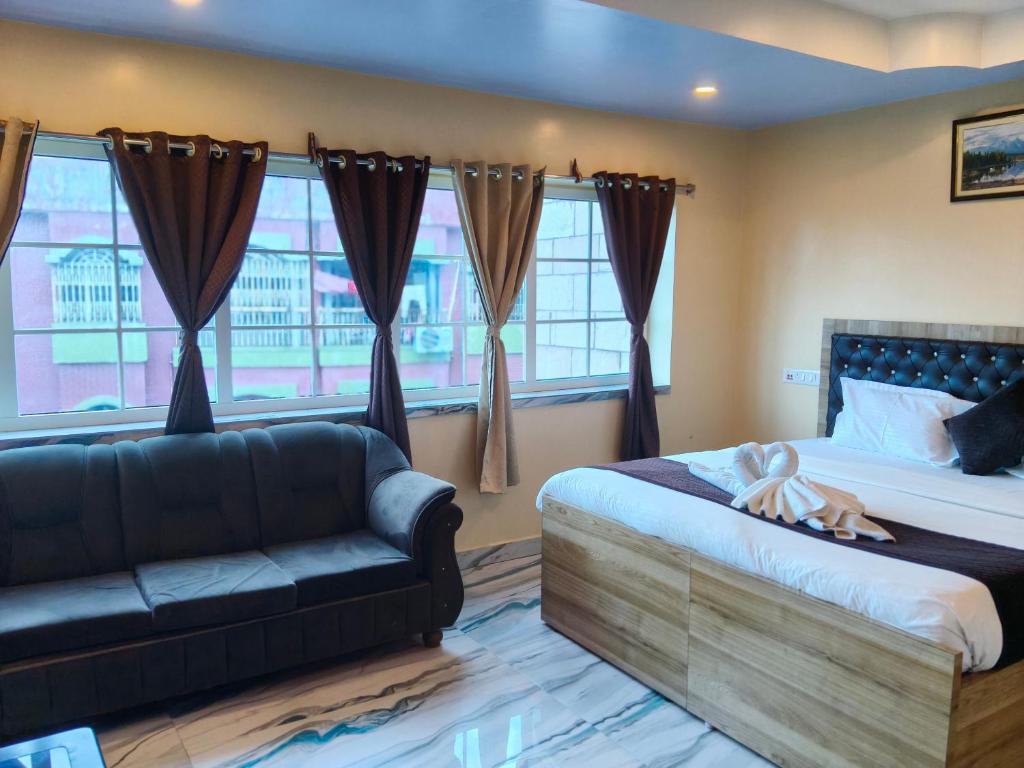 a bedroom with a bed and a couch and windows at Hotel Mahal in Uchalon