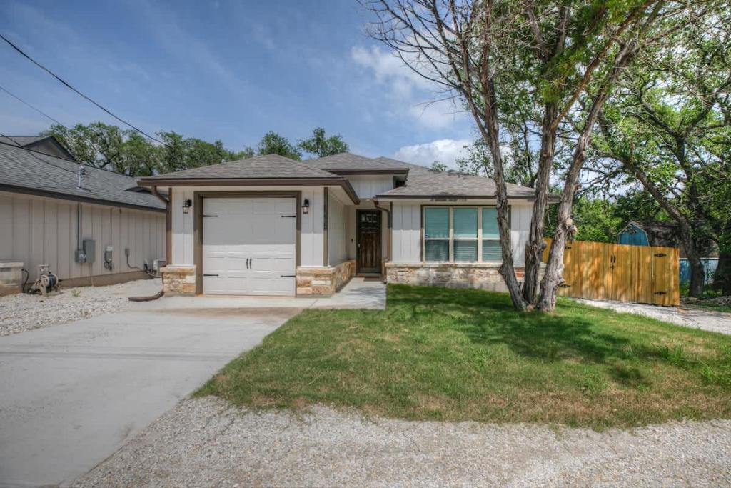 ein Haus mit einer Garage und einem Baum in der Unterkunft Pristine 3-bedroom Home Near Canyon Lake! in Cranes Mill