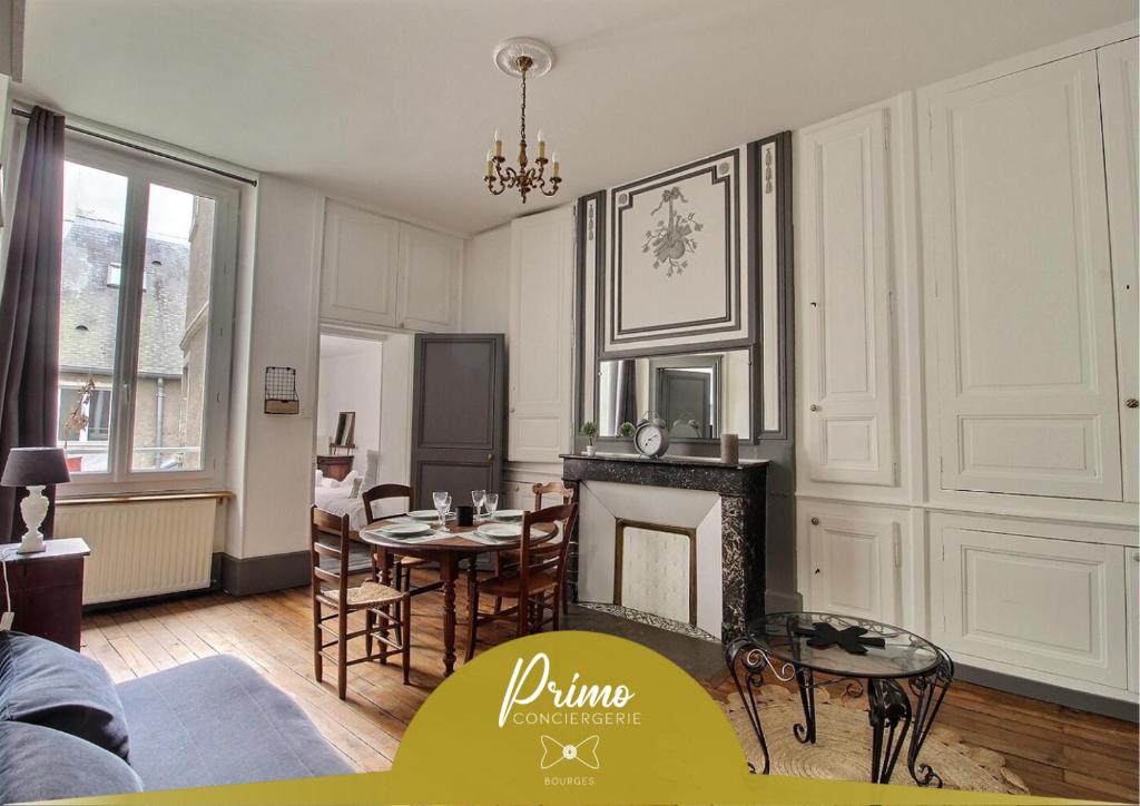 ブールジュにあるLe Logis d'Henri by PRIMO C0NCIERGERIEの暖炉とテーブルと椅子のあるリビングルーム