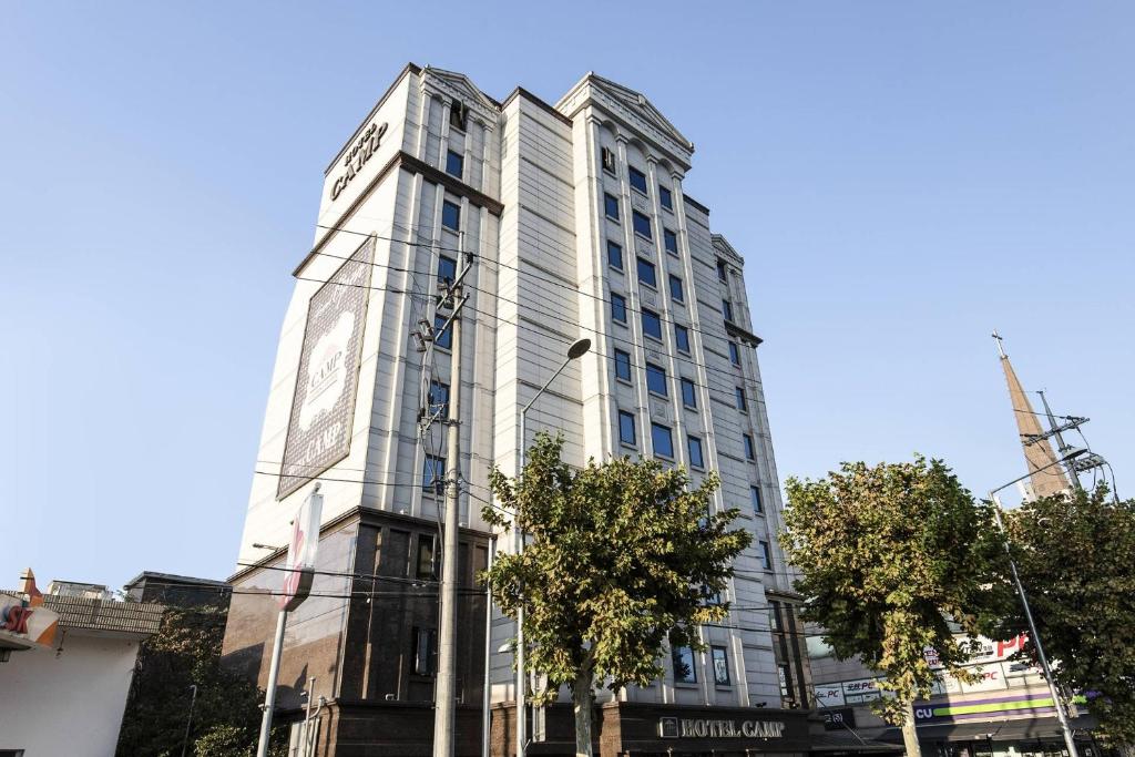 a tall white building with a sign on it at Camp Hotel in Seoul