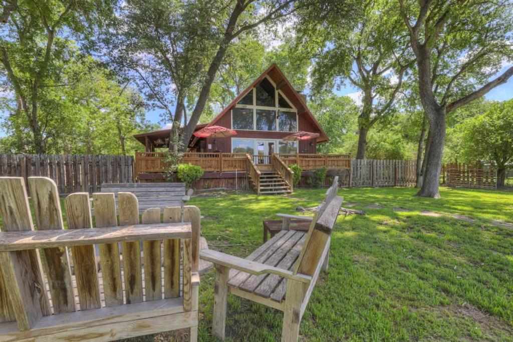 two wooden benches sitting in front of a house at Gettin' Guada loopy with Hot Tub & Riverfront in Schumannsville