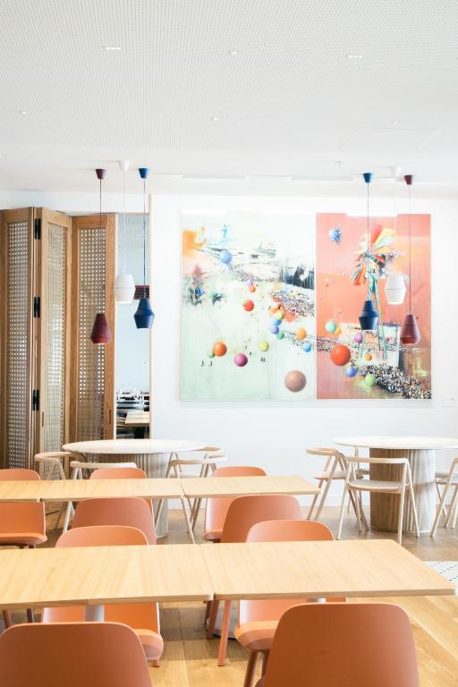 A light-filled breakfast or event room is furnished with rows of flexible tables and warm-toned chairs.