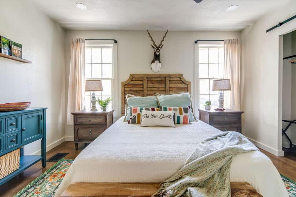 a bedroom with a large bed and two windows at Southern Charm - Near Main With Hot Tub in Fredericksburg